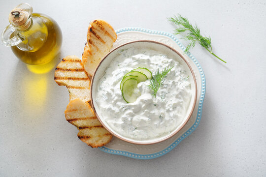 Tzatziki salad with roasted bread in white bowl on white background. Homemade Tzatziki salad with olive oil. Top view.