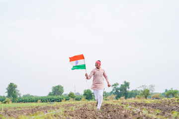 yong indian farmer holding indian flag standing at field