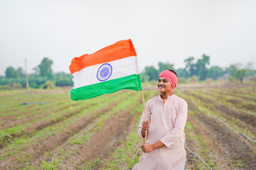 yong indian farmer holding indian flag standing at field