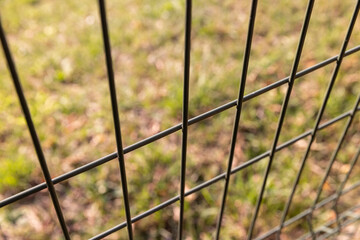 a thin lattice fence against a blue sky background, a small thin fence dividing the territory...