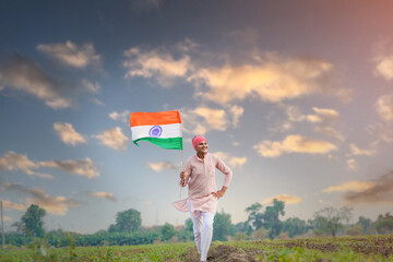 yong indian farmer holding indian flag standing at field