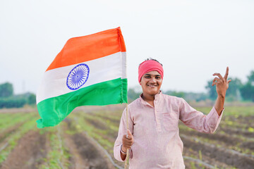yong indian farmer holding indian flag standing at field