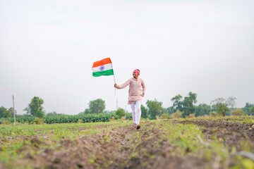 yong indian farmer holding indian flag standing at field