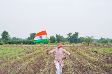 yong indian farmer holding indian flag standing at field