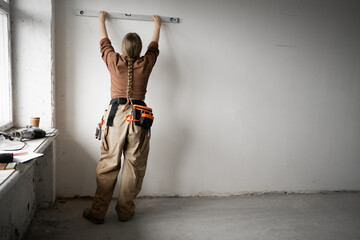Handyman measuring wall with spirit level. Repairman working home renovation and construction.