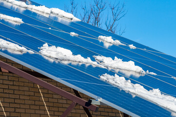Snow-covered solar panels on a rooftop showcase winter challenges for renewable energy generation.