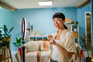 Smiling female Japanese video blogger record new video for subscribers