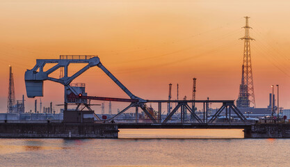 Riveted bascule bridge during a sunset with harbor activity on the background, Port of Antwerp, Belgium.
