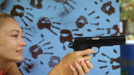 Woman shoots at shooting range with pneumatic gun. Outdoors entertainment for tourists in...