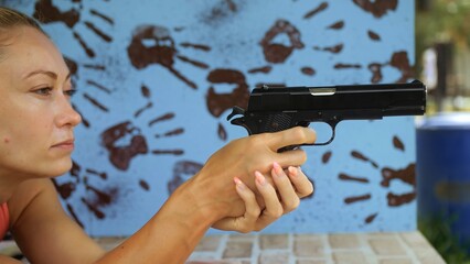 Woman shoots at shooting range with pneumatic gun. Outdoors entertainment for tourists in...