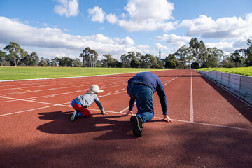 A heartwarming moment of a father and son preparing to race on an athletics track. Concept of...