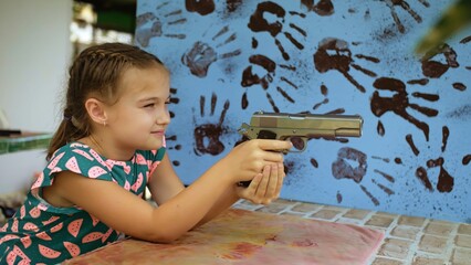 Little girl shoots at shooting range with gun. Outdoors entertainment for tourists in Thailand....