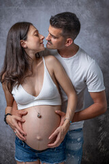 A man hugs and is about to kiss his partner who is pregnant