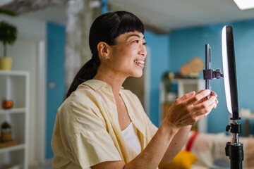 female japanese video blogger set up equipment and prepare for filming