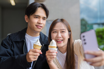 Couple holding and eating ice cream outdoors during summer