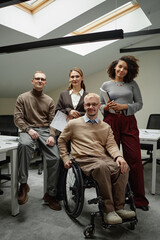 Diverse group of young adult professionals posing in modern office, including Caucasian man with...