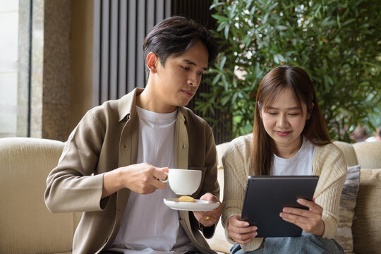 Couple using tablet computer in cafe while having coffee - Powered by Adobe