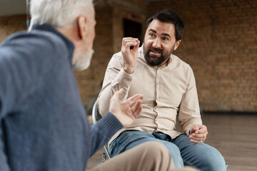Bearded man explaining something to senior colleague during meeting