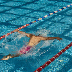 A swimmer performs the butterfly stroke in an outdoor swimming pool lane on a sunny day. Concept of...
