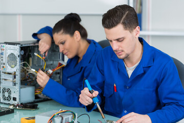 team of students examining and repairing computer parts