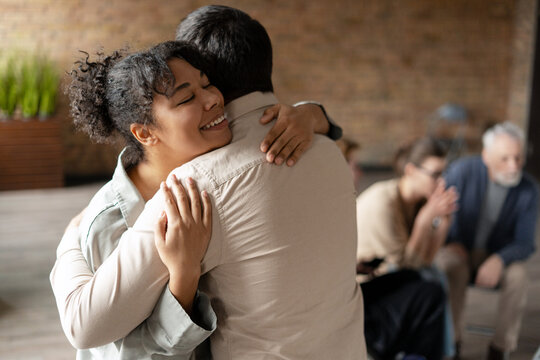 Happy african american woman hugging coach at therapy session