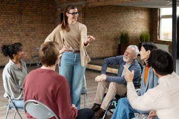 Coach leading a support group meeting with diverse people including a senior man in a wheelchair