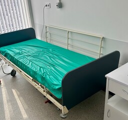 Modern hospital bed in clean, bright medical room. Empty healthcare facility interior with green...