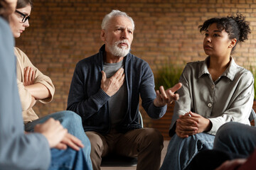 Senior man talking about his problems during group therapy session