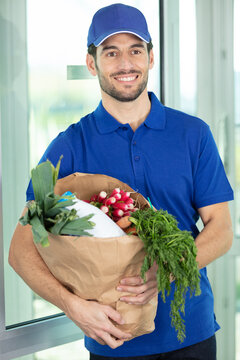 smiling delivery man holding recycle grocery shopping bag