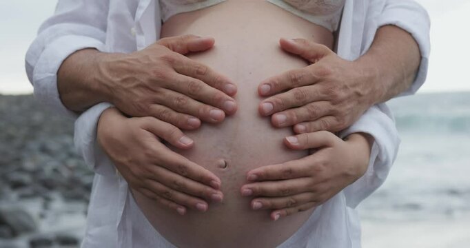 Young couple having tender moment together on the beach with pregnant belly - Maternity and family concept