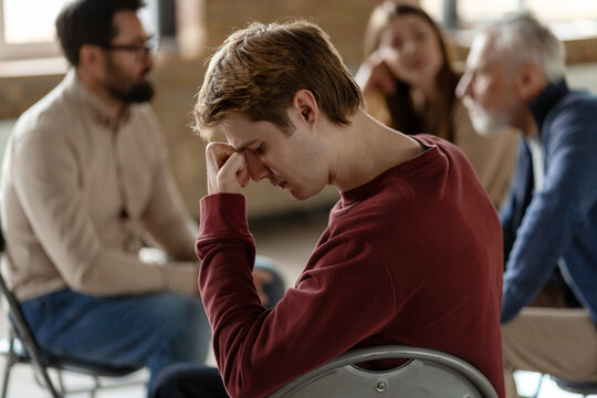 Young man suffering from anxiety during group therapy session