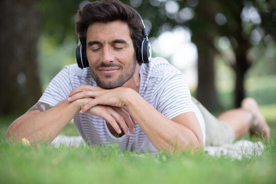young man listening to music in green summer forest