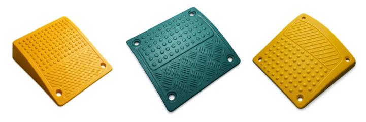 Set of tactile curb ramp plates in yellow and teal plastic with bolt holes and raised dot textures on black background