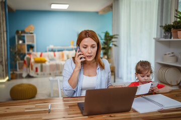 Focused mother work on laptop online while daughter use cellphone