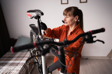Active middle aged woman repairing and maintaining bicycle at home in her free time
