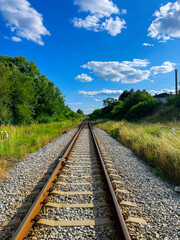 Railway tracks stretching into the distance through a lush green landscape. Summer countryside view...
