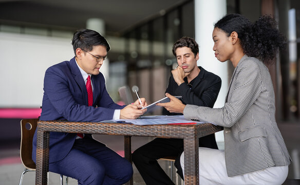Latino man, African American businessperson, Asian manager brainstorming startup small business strategy. Multiracial businesswoman and colleague serious working on planning. Diversity people team.