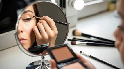 Woman applying eyeliner with makeup mirror - Powered by Adobe