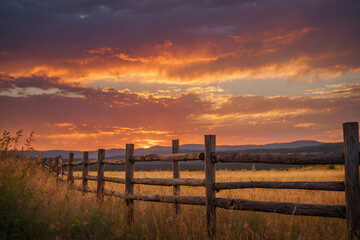 Fototapeta premium Late summer sky glowing in pink-orange tones behind a blurred glass bottle edge placed on a low surface with diffused foreground light and clean upper clarity, the HD image presents