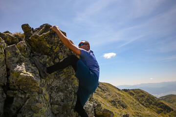 Determined hiker ascending steep rock face, enjoying challenging climb amidst breathtaking mountain...