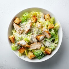 A delicious Caesar salad in a white bowl, featuring grilled chicken, romaine lettuce, croutons, and Caesar dressing.