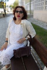 Elegant woman relaxing on bench in city park