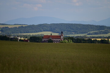 Scenic view of the church and village of Bolatice surrounded by fields, forests, and distant hills...