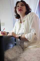 Businesswoman writing notes and working on tablet in modern office