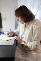 Businesswoman writing notes in notebook at office desk