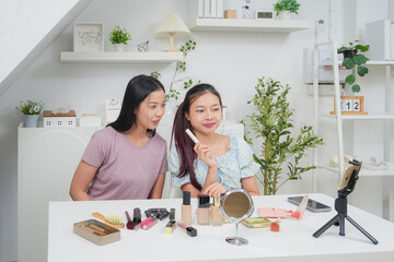 Two beautiful professional asian young woman blogger recording vlog video with make up cosmetic at home online influencer on social media concept. Live streaming viral 