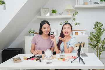 Two beautiful professional asian young woman blogger recording vlog video with make up cosmetic at home online influencer on social media concept. Live streaming viral 