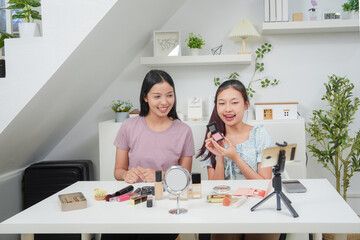 Two beautiful professional asian young woman blogger recording vlog video with make up cosmetic at home online influencer on social media concept. Live streaming viral 