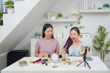 Two beautiful professional asian young woman blogger recording vlog video with make up cosmetic at home online influencer on social media concept. Live streaming viral 