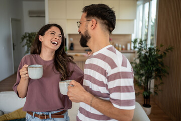 Happy couple laughing and drinking coffee in modern kitchen